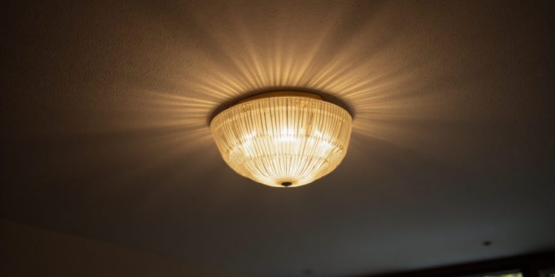 Homeowner changing a ceiling light fixture safely with power turned off.